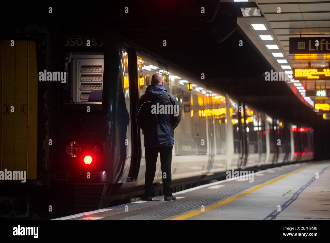 Il treno passeggeri di Birmingham si fermò aspettando con un autista che guardava la metropolitana piattaforma e riflessioni di notte durante il blocco pandemico, nessun passeggero Foto Stock