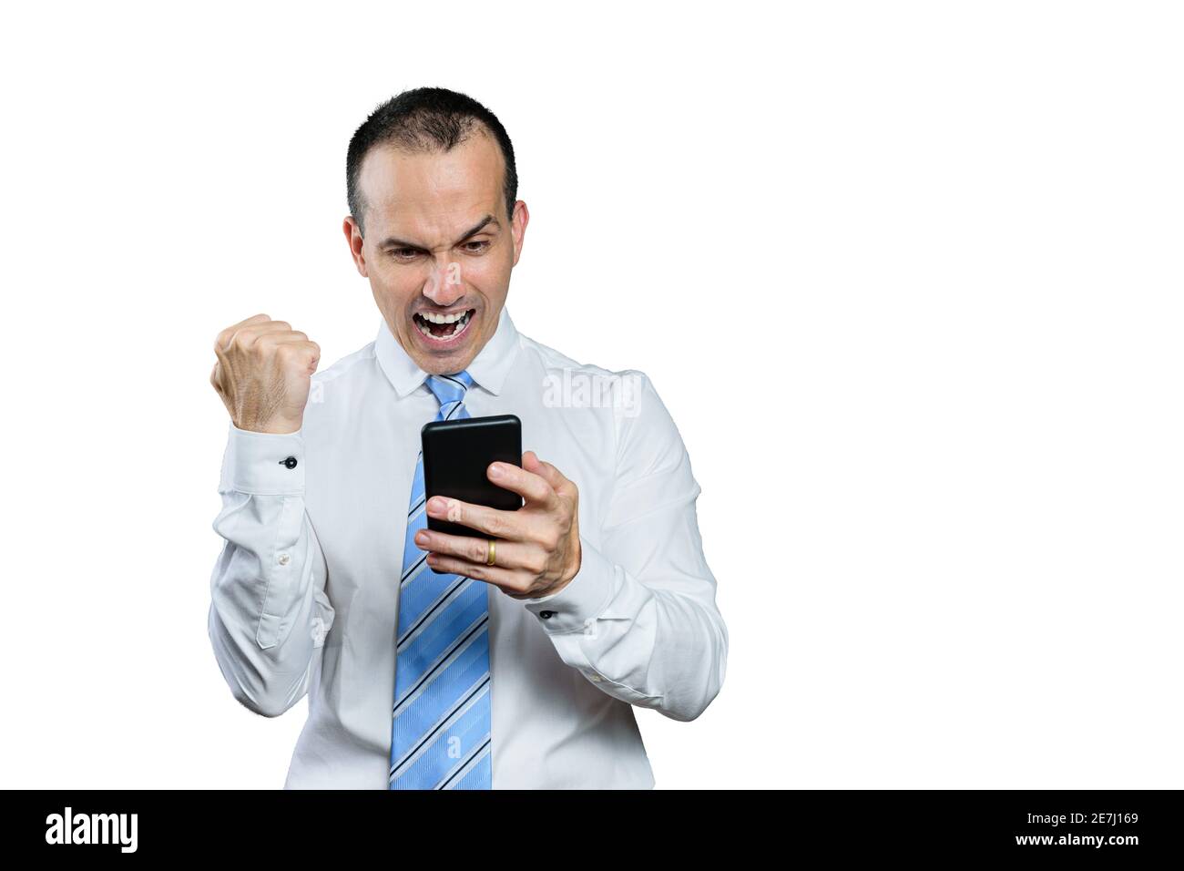 Uomo brasiliano maturo, in abbigliamento formale, festeggiando con il suo smartphone e pugno clenched. Foto Stock