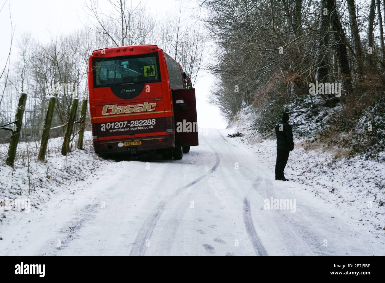 Un pullman rosso bloccato su una collina innevata in inverno, Regno Unito Foto Stock