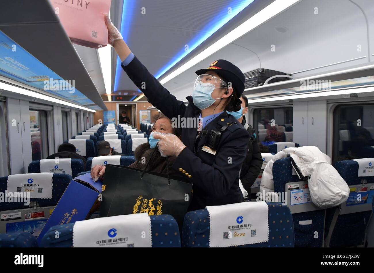 (210130) -- NANCHANG, 30 gennaio 2021 (Xinhua) -- Wang Ajing, un assistente del China Railway Nanchang Bureau Group Co., Ltd., aiuta un passeggero a mettere i suoi bagagli a bordo di un treno il 26 gennaio 2021. Wang Ajing, di 30 anni, che proviene dalla città di Xianyang, nella provincia di Shaanxi, nella Cina nord-occidentale, sta ora fungendo da assistente del China Railway Nanchang Bureau Group Co., Ltd. Prima di lasciare la sua città natale nel 2008, i genitori di Wang le hanno dato una foto di famiglia, che ha portato con lei da allora. La madre di Wang, per qualche ragione, non era in grado di partecipare al suo matrimonio quando si sposò a Jiangxi nel 201 Foto Stock