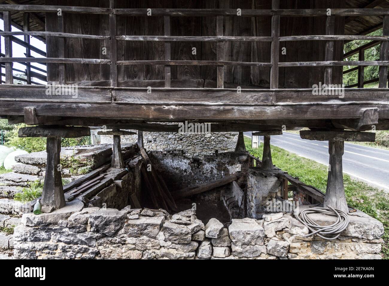 Grande megalito verticale che sostiene una vecchia casa di legno Foto Stock