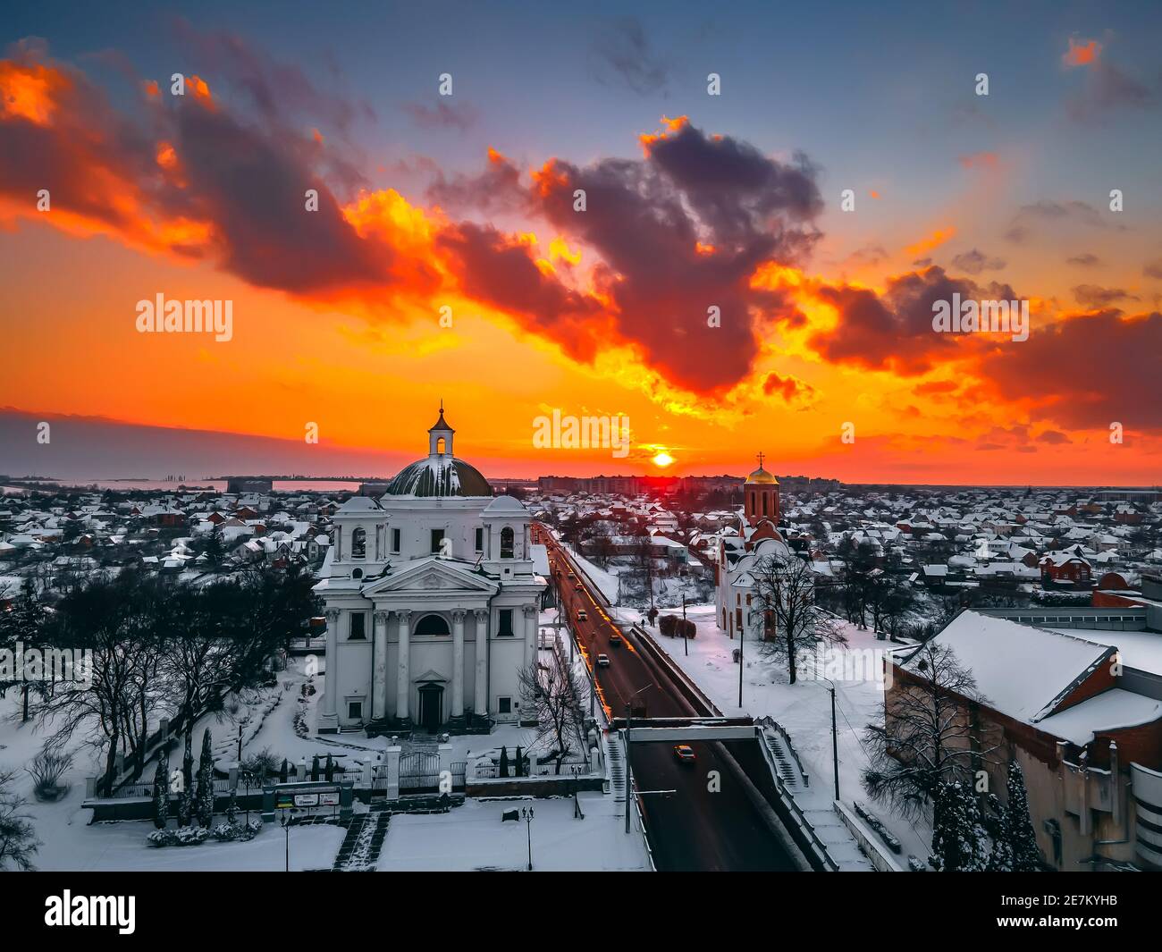 Vista aerea della cattedrale e della chiesa nella piccola città europea coperta di neve al luminoso tramonto d'inverno splendidi tramonti e nuvole. Drone. Inverno. Ukrain Foto Stock