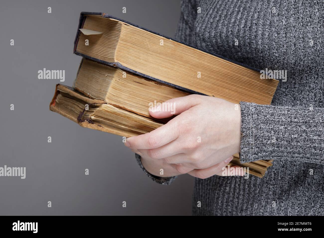 mano di una persona invisibile tiene hugs un vecchio libro. Foto Stock