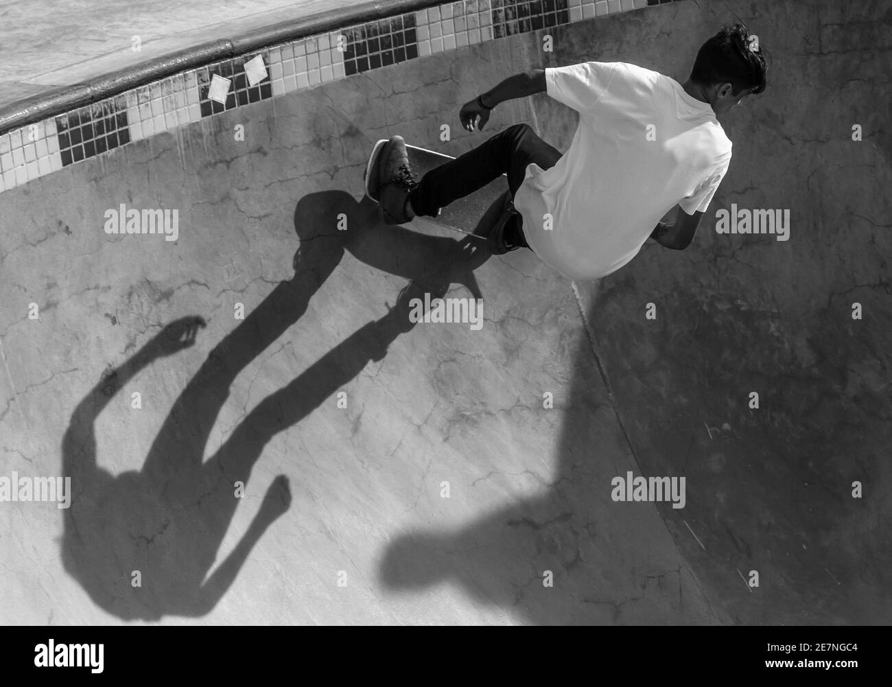 Immagine in scala di grigi di uno skateboard maschile giovane in uno skatepark Foto Stock