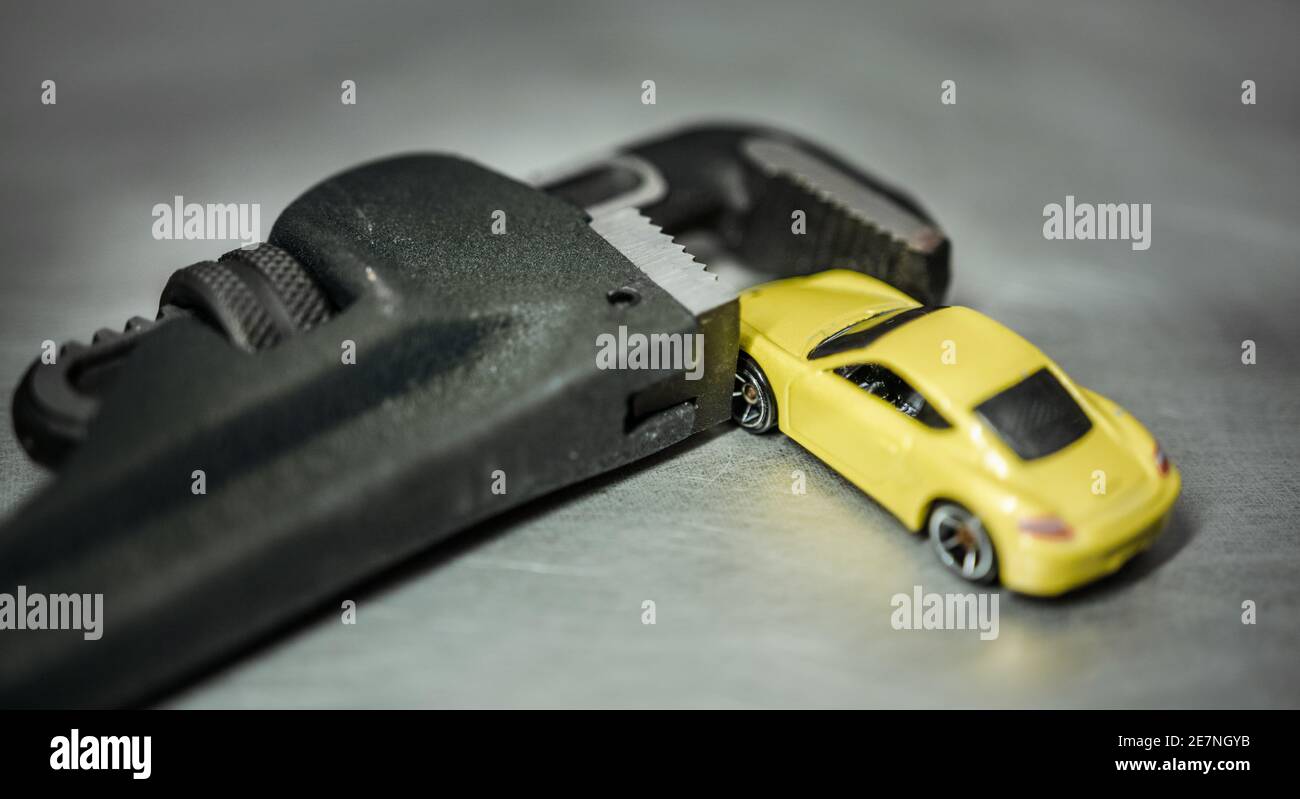 Macchina sportiva in miniatura intrappolata nella mascella della chiave a tubo. Foto Stock
