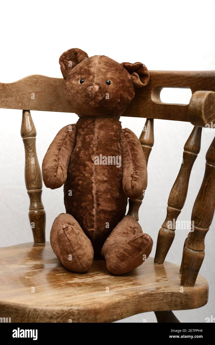 orsacchiotto giocattolo seduto in una vecchia poltrona di legno d'epoca Foto Stock