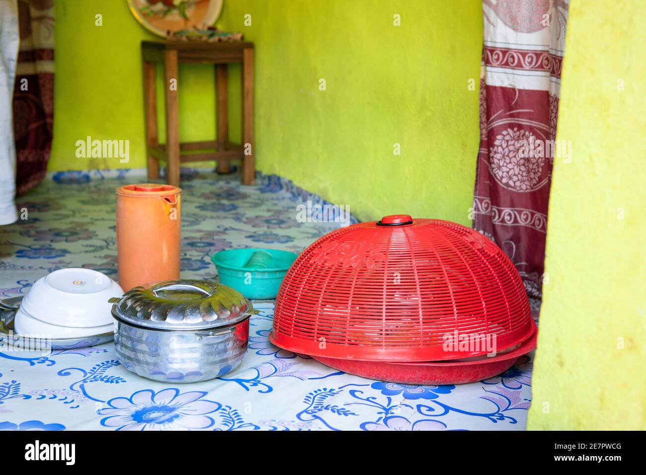 Piatti africani cucinati e serviti in piatti colorati. Interno della modesta vintage stile povera cucina, preparato pasto posato a terra. Vita reale Foto Stock