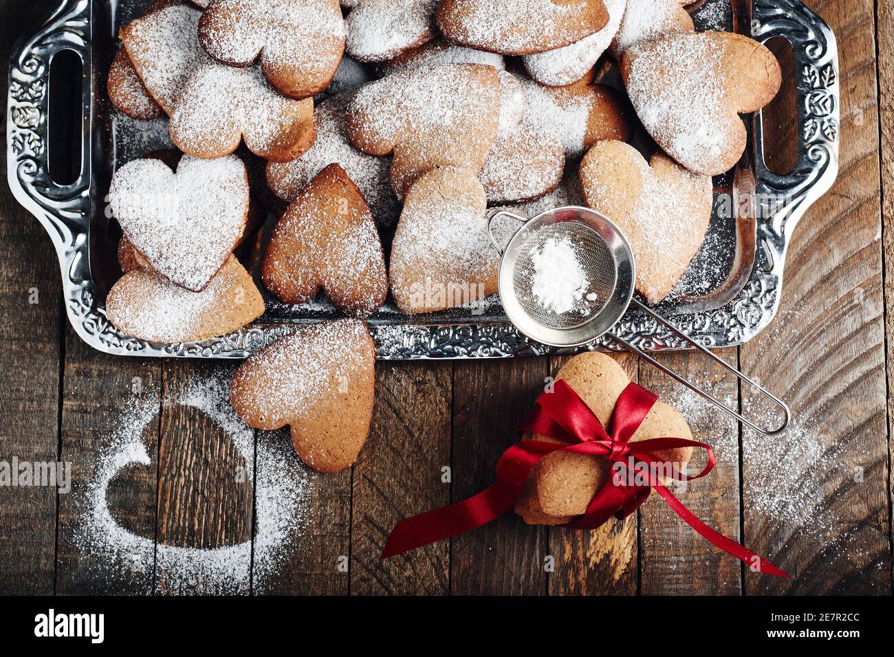 Biscotti shortbread a forma di cuore cosparsi di zucchero a velo su un vassoio Foto Stock