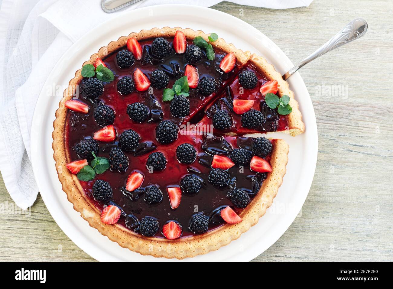 Crostata estiva di frutti di bosco con more e fragole su un tavolo di legno. Foto Stock