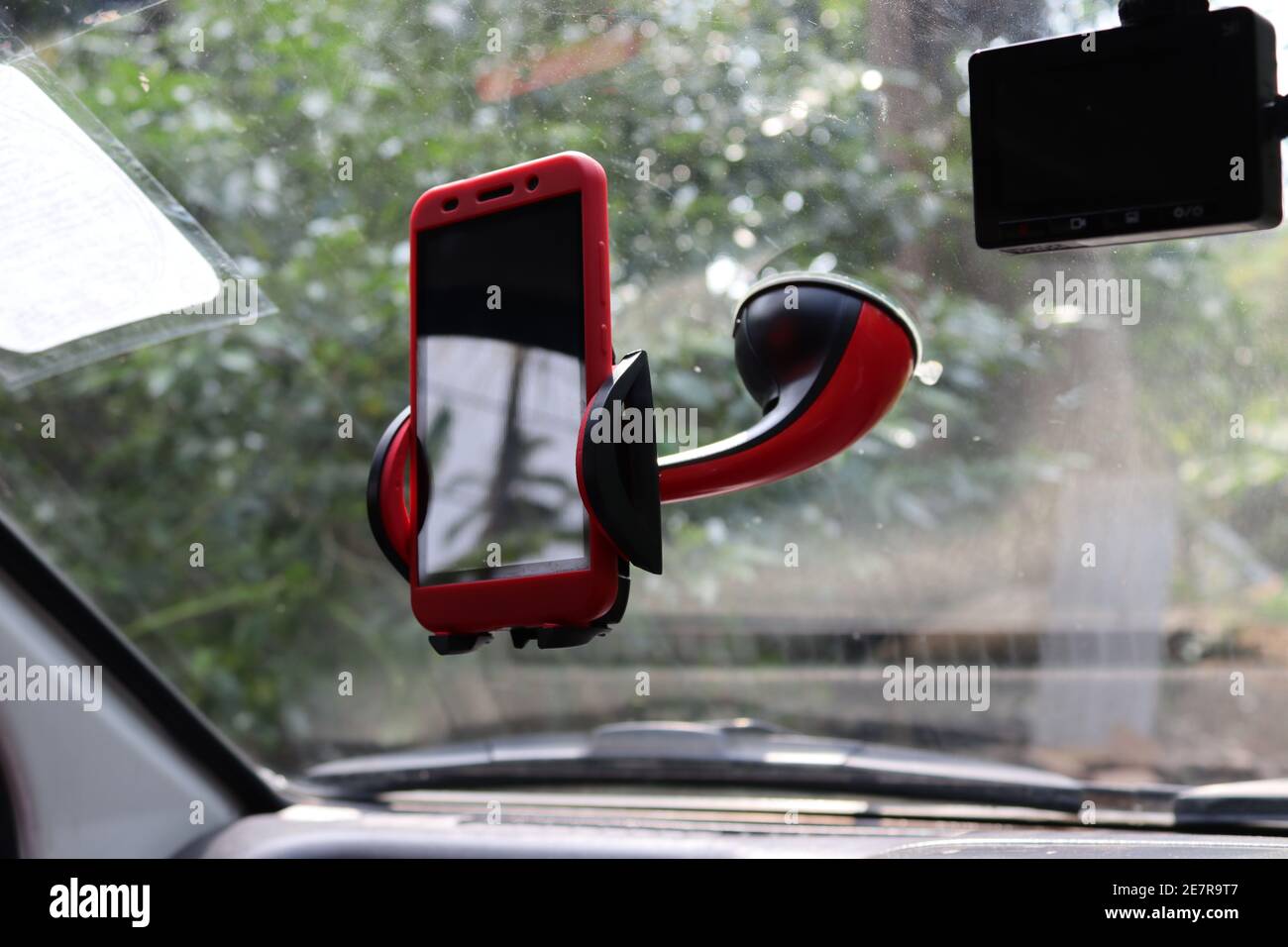 Un telefono cellulare con un supporto telefonico in rosso, in auto. Foto Stock