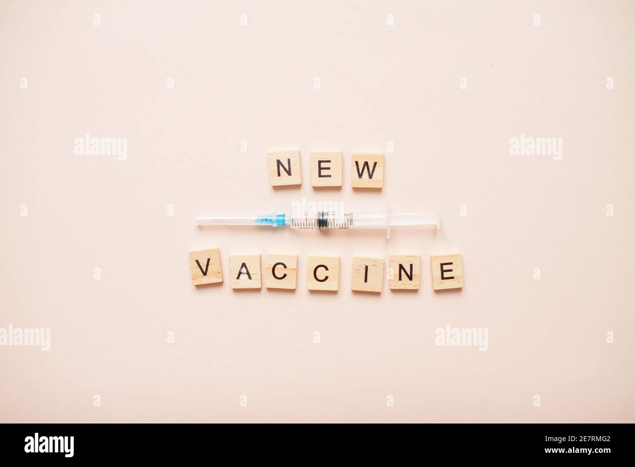 Frase nuovo vaccino fatto da blocchi di legno su una luce sfondo rosa Foto Stock
