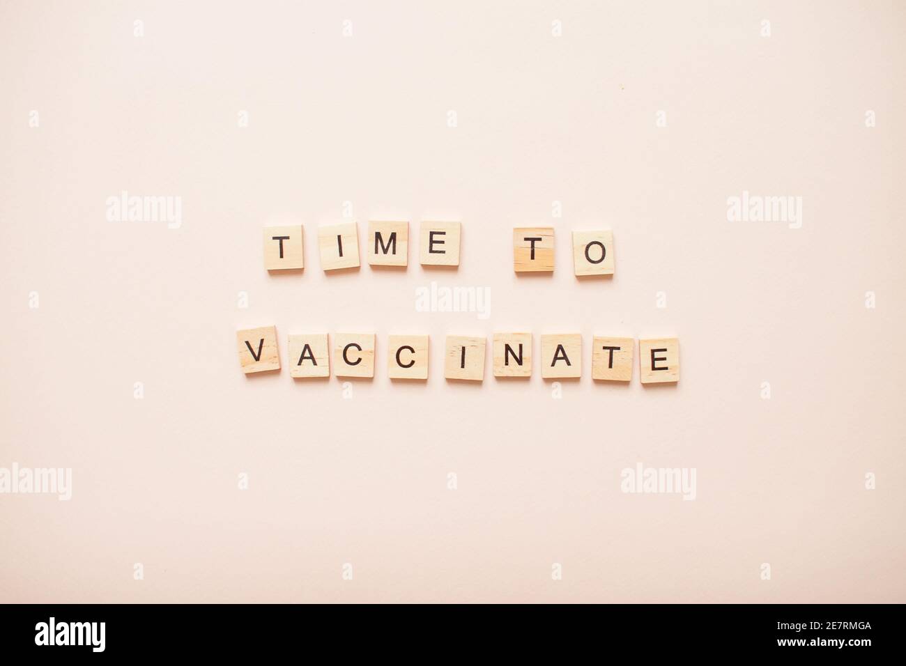 Frase tempo di vaccinare fatto da blocchi di legno su un sfondo rosa chiaro Foto Stock