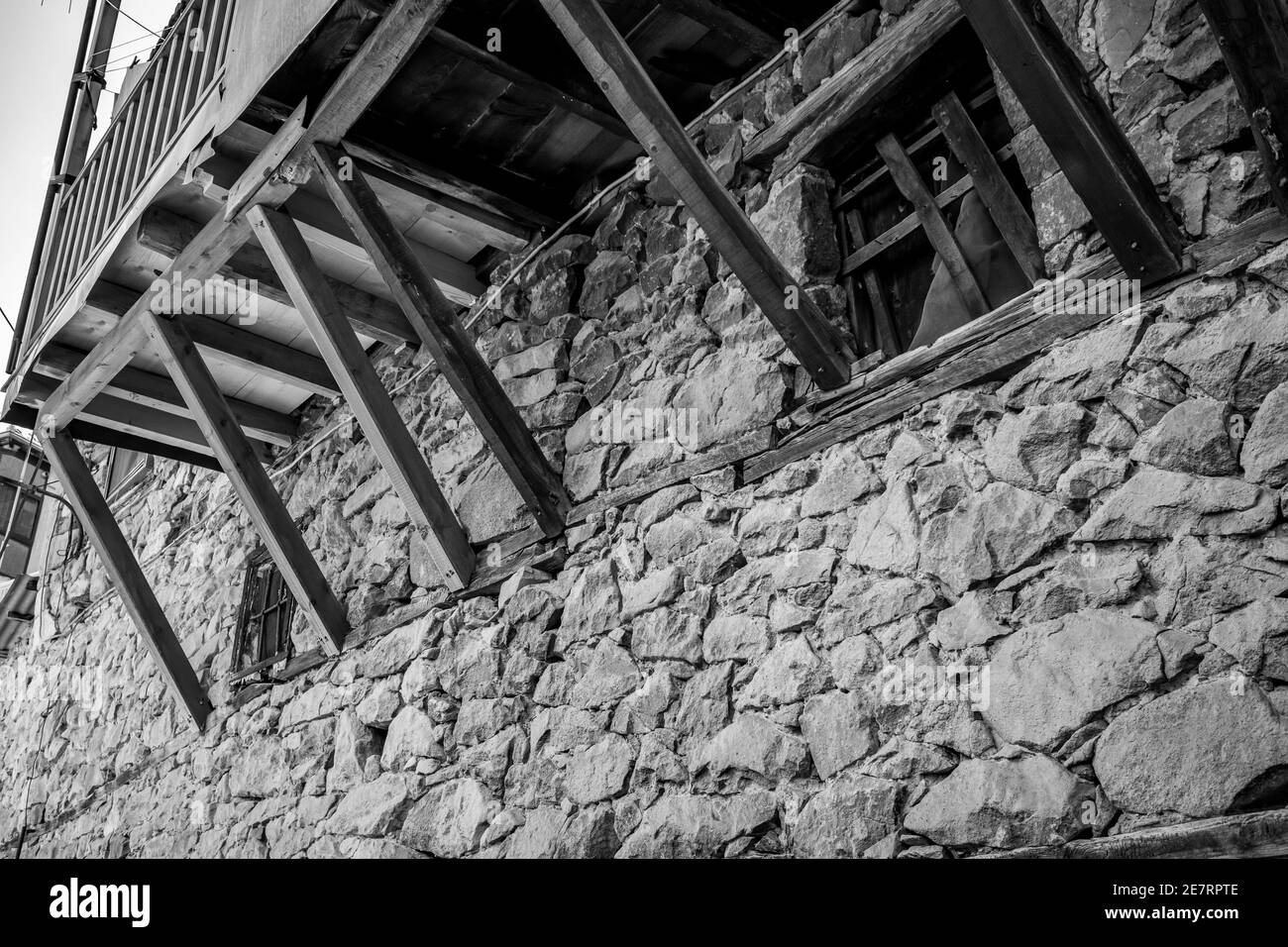 Spring Street basso angolo vista in bianco e nero, vecchio balcone in legno, città di Metsovo, Epiro, Grecia. La struttura è popolare stazione sciistica invernale greca con vecchie case in stile balcanico Foto Stock