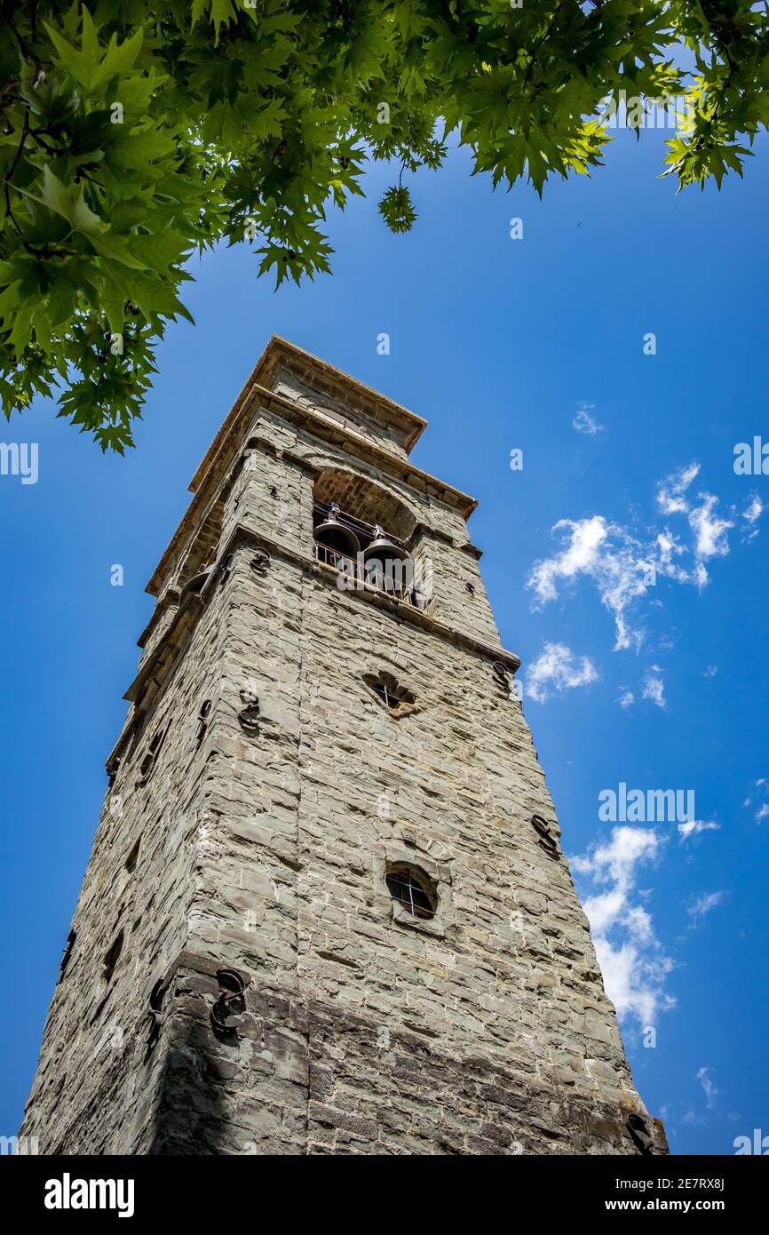 Vista a basso angolo di Spring Street, campanile in pietra, ramo d'albero e cielo dalla città di Metsovo, Epiro, Grecia. La struttura è popolare stazione sciistica invernale greca con vecchie case in stile balcanico Foto Stock
