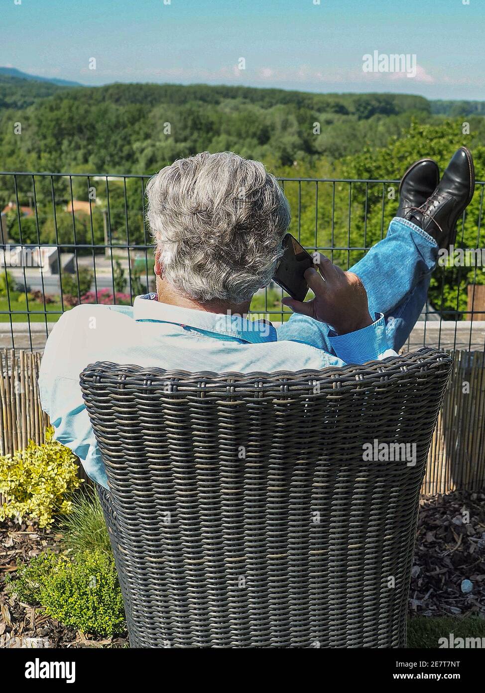 Uomo d'affari anziano con smartphone che effettua la chiamata in giardino. Foto Stock