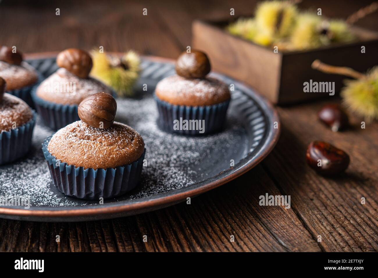 Muffin a base di purè di castagne dolci e cacao, ricoperti di castagne pelate e cotte, spolverati con zucchero in polvere su rustico fondo di legno Foto Stock