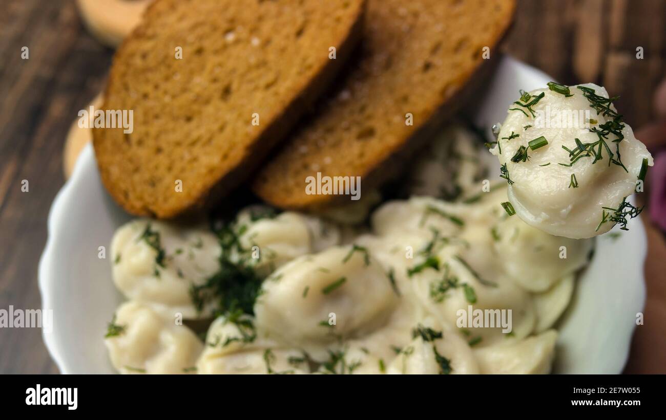 Vista dall'alto gnocchi cosparsi di erbe, cibo fatto in casa, gnocchi in un piatto su un vassoio di legno, cibi appetitosi, cucina in cucina. Foto Stock