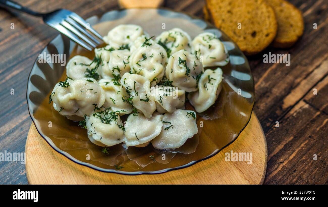 Gnocchi in un piatto su un vassoio di legno, delizioso cibo fatto in casa, gnocchi decorati con erbe, cibo russo, gnocchi cottura. Foto Stock