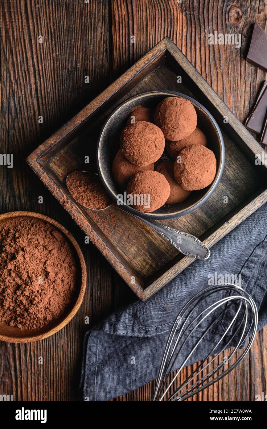 Delizioso tartufo di cioccolato fatto in casa coperto di cacao in polvere su rustico sfondo di legno Foto Stock