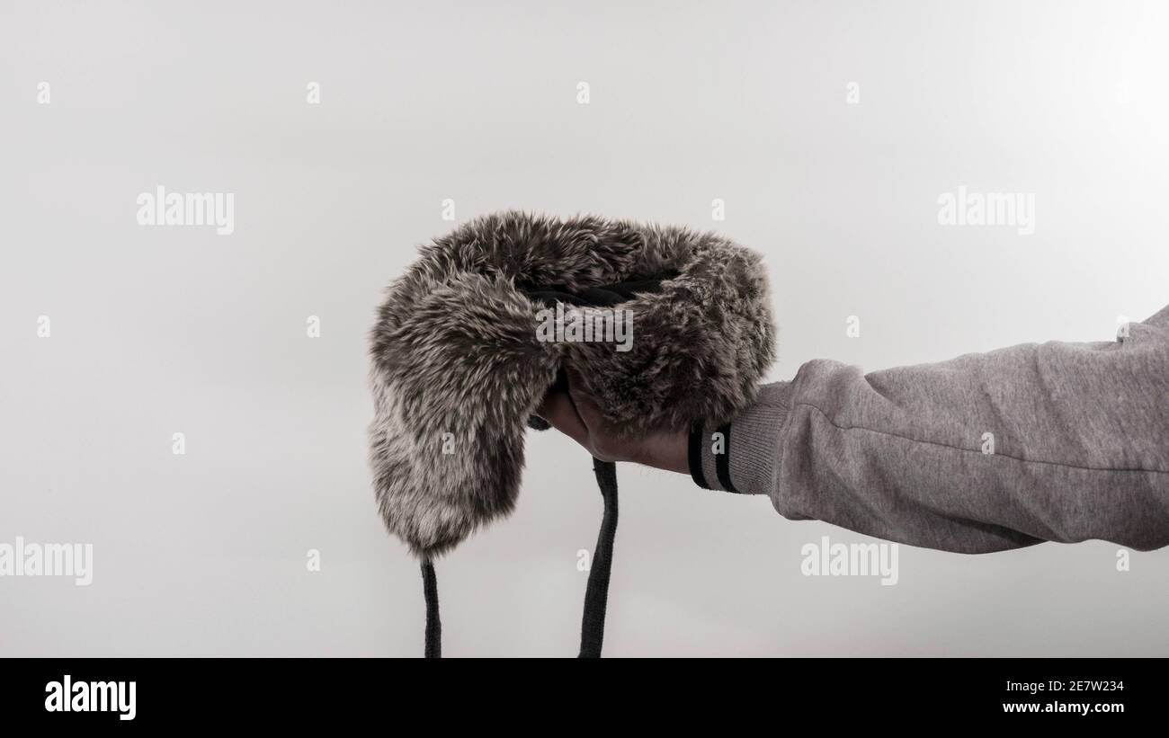 Gettando una moneta ai poveri su uno sfondo bianco, gettando una moneta in un cappello con parapetto, finanze, denaro piggy banca. I senzatetto mendicante Foto Stock