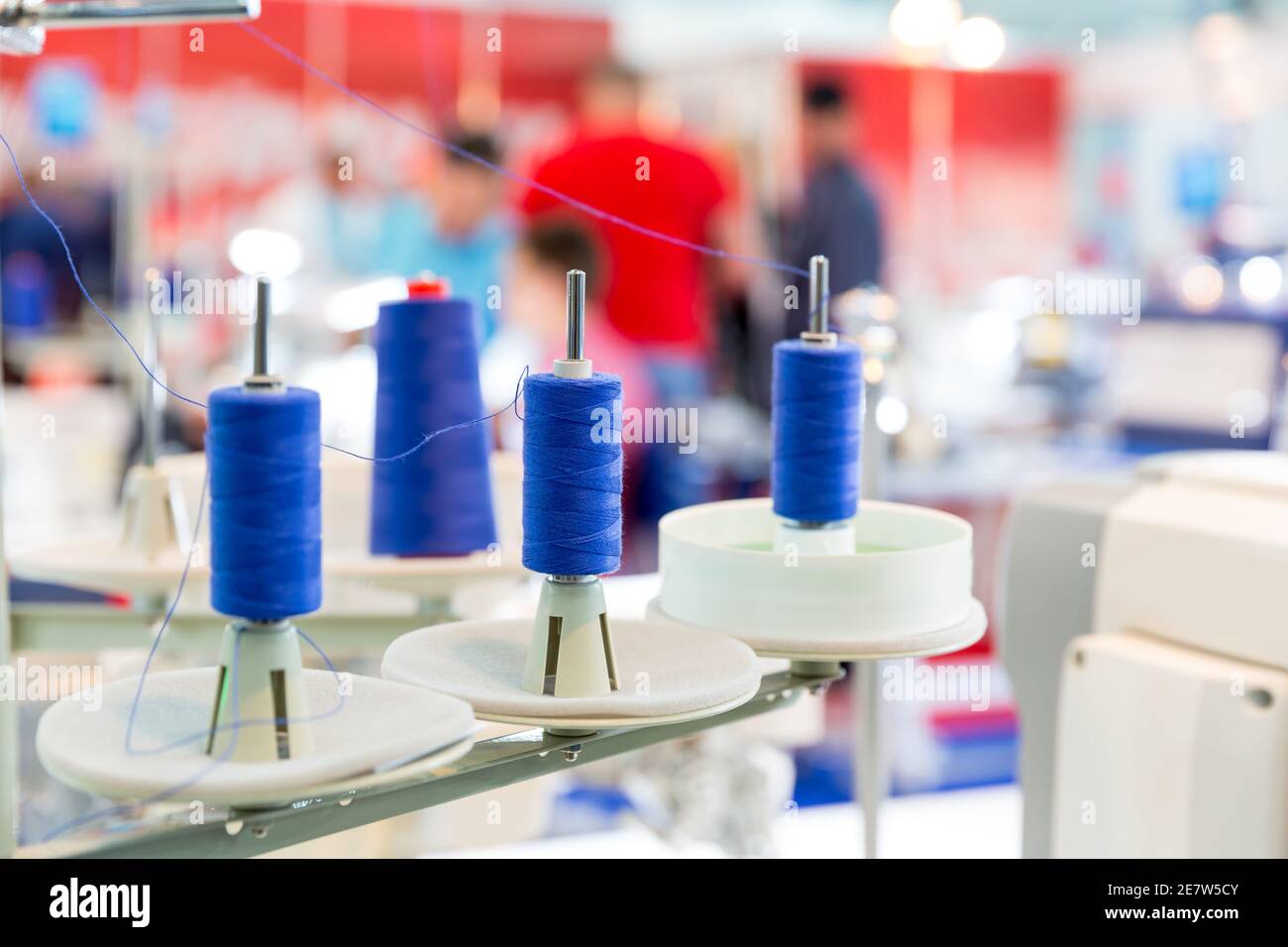 Rocchetti di fili blu su macchina da cucire, closeup. Fabbrica di tessuti, tessitura, produzione tessile, industria dell'abbigliamento Foto Stock