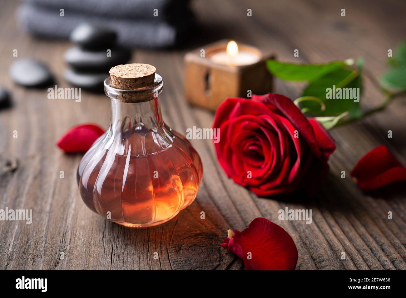 Acqua di rosa infusa fresca fatta in casa in una bottiglia di vetro per routine di cura della pelle su sfondo rustico di legno Foto Stock