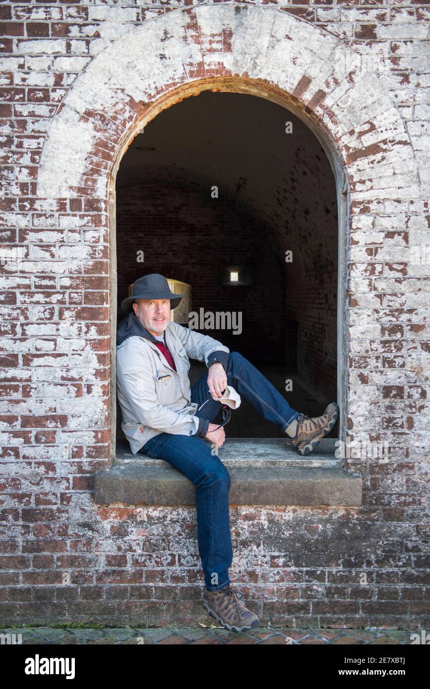 Un uomo siede nella finestra bene nel cortile interno conosciuto come il terreno di parata a Fort Macon state Park in Atlantic Beach, NC. Foto Stock