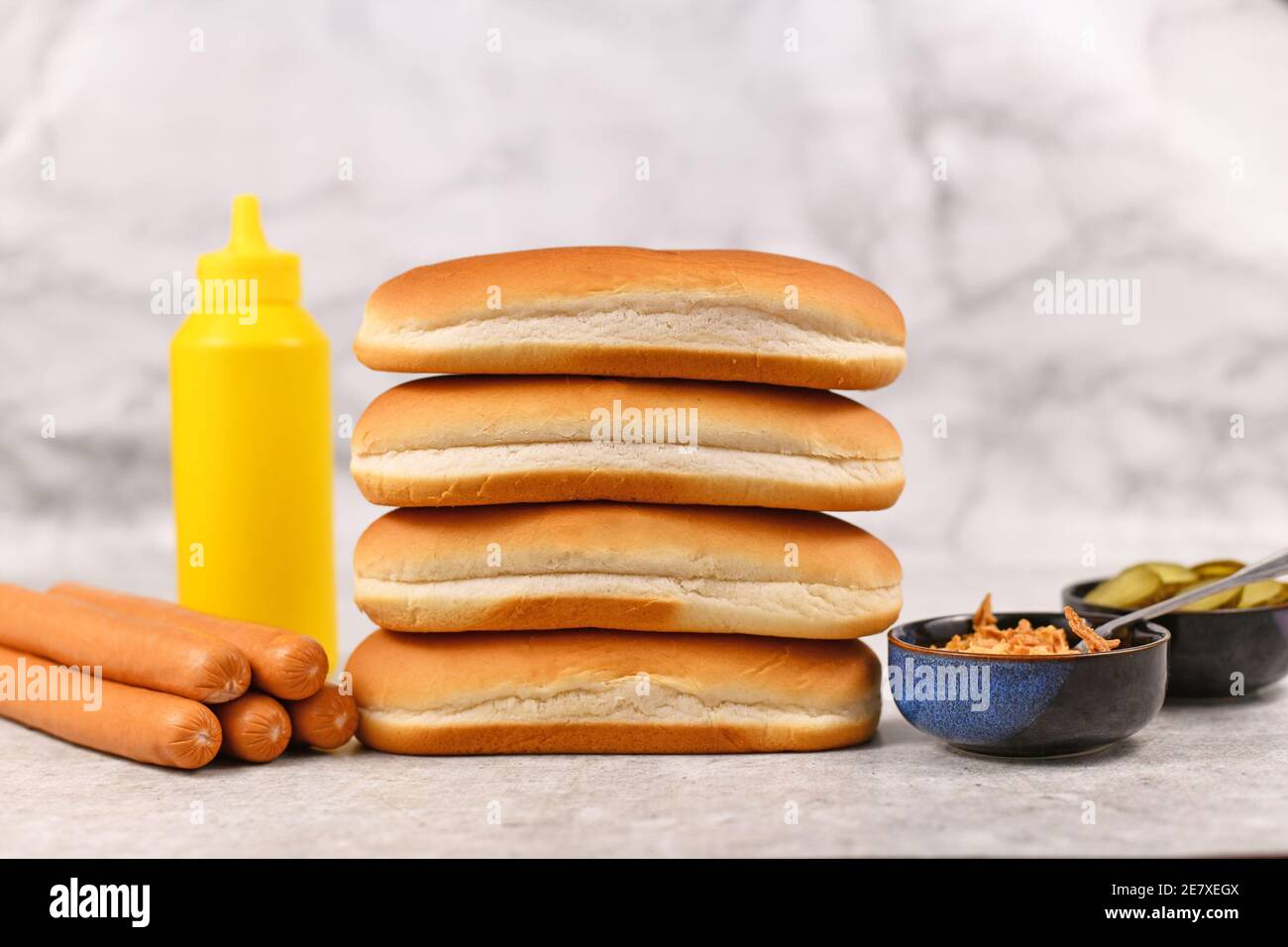 Ciambelle impilate di cani caldi circondate da ingredienti Foto Stock