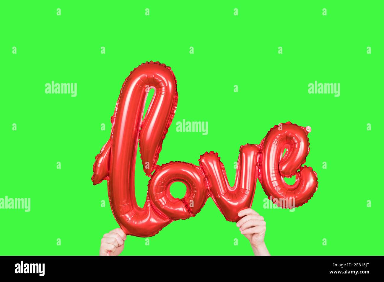 Amore rosso di parola d'oro fatto di palloncini gonfiabili in mani isolate su schermo verde. Le lettere rosse del pallone di alluminio, concetto di romanticismo, San Valentino Foto Stock