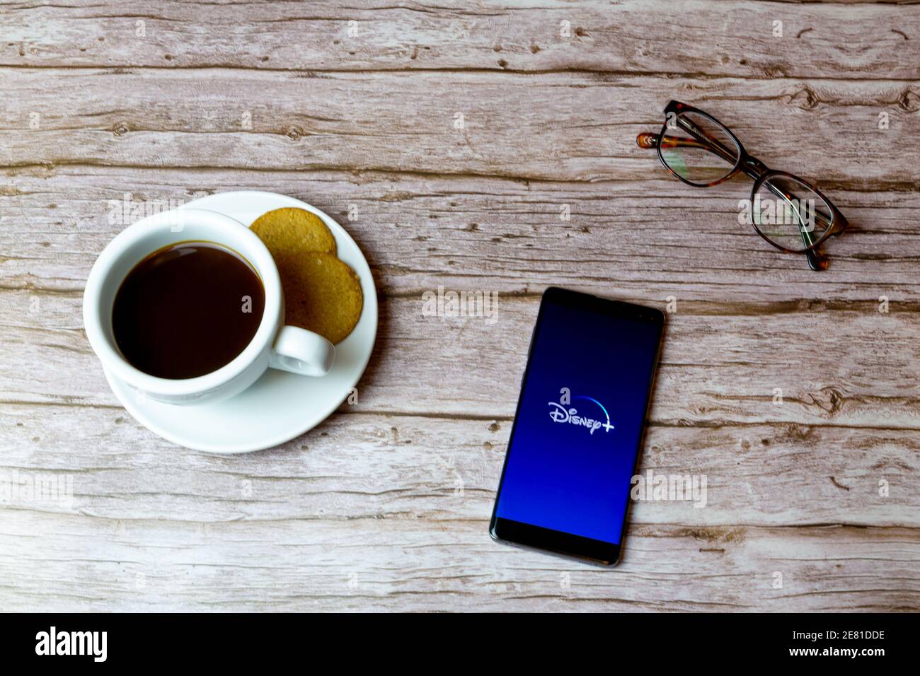 Un telefono cellulare o un telefono cellulare posato su un legno tavolo con l'app disney plus che apre anche un caffè e bicchieri Foto Stock