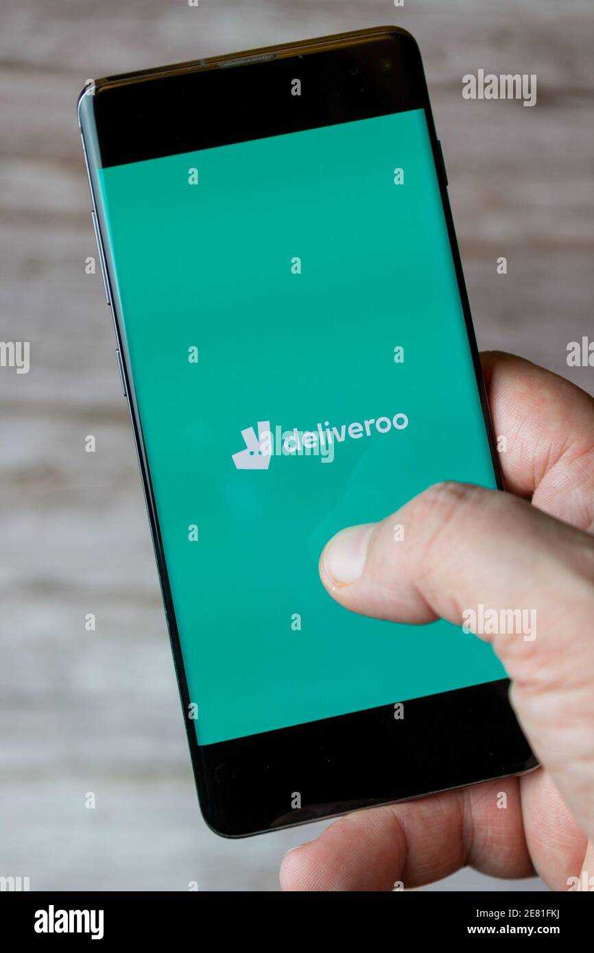 Una mano che tiene un telefono cellulare o cellulare con l'applicazione deliveroo si apre sullo schermo Foto Stock