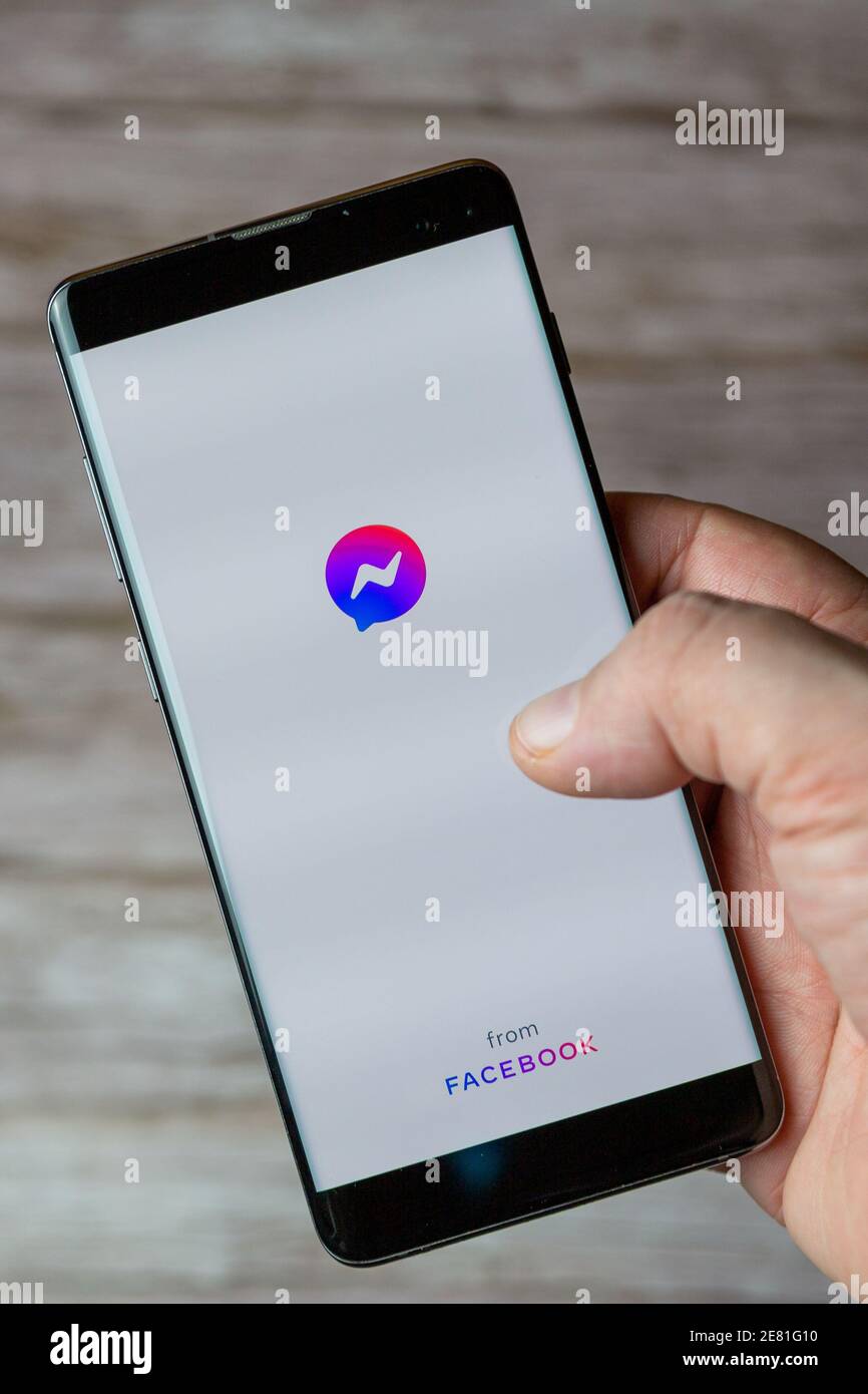 Una mano che tiene un telefono cellulare o cellulare con L'applicazione Facebook Messenger si apre sullo schermo Foto Stock