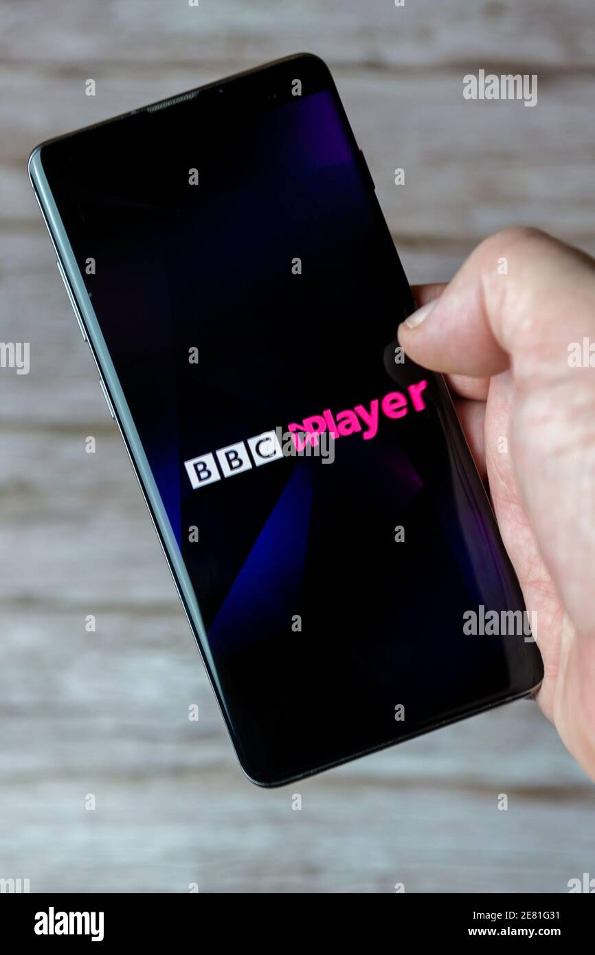 Una mano che tiene un telefono cellulare o cellulare con L'app BBC iPlayer si apre sullo schermo Foto Stock