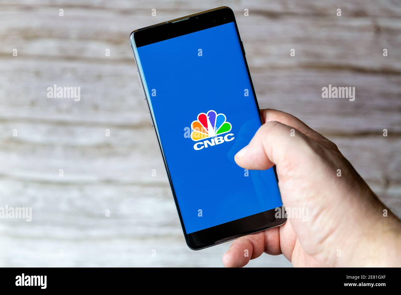 Una mano che tiene un telefono cellulare o cellulare con L'app CNBC si apre sullo schermo Foto Stock