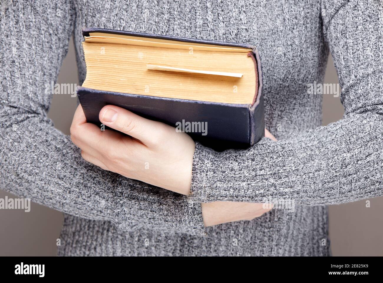 mano di una persona invisibile tiene hugs un vecchio libro. Foto Stock