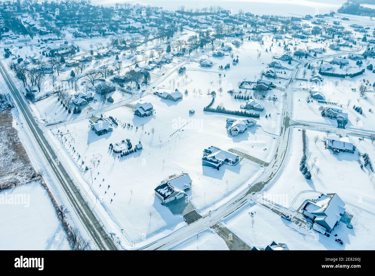 Sorvolando grandi case con grandi cantieri in un quartiere suburbano subito dopo una neve fresca. Foto Stock