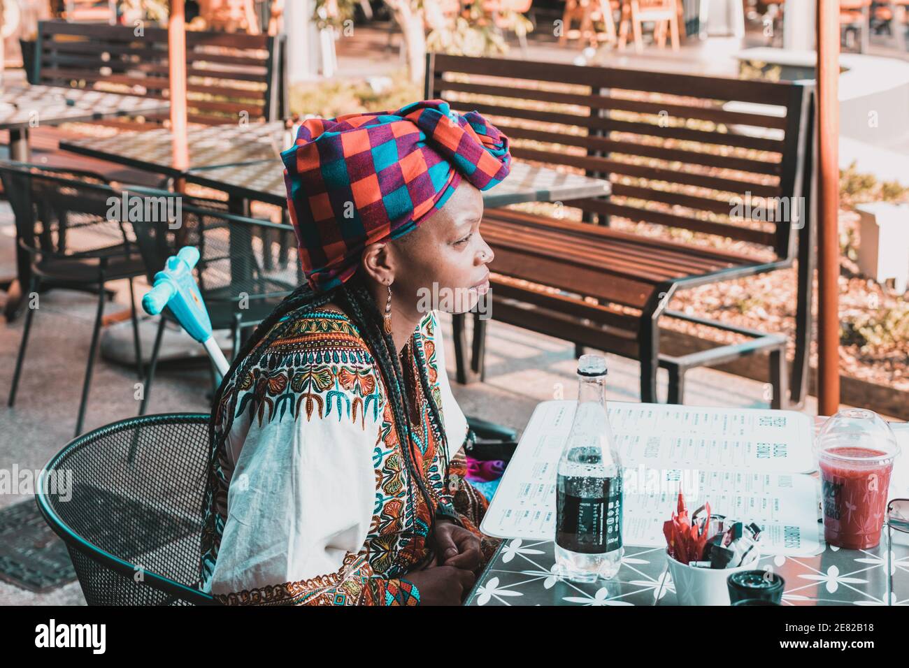 Donna africana alla moda che indossa una sciarpa per la testa con un cibo menu aperto Foto Stock
