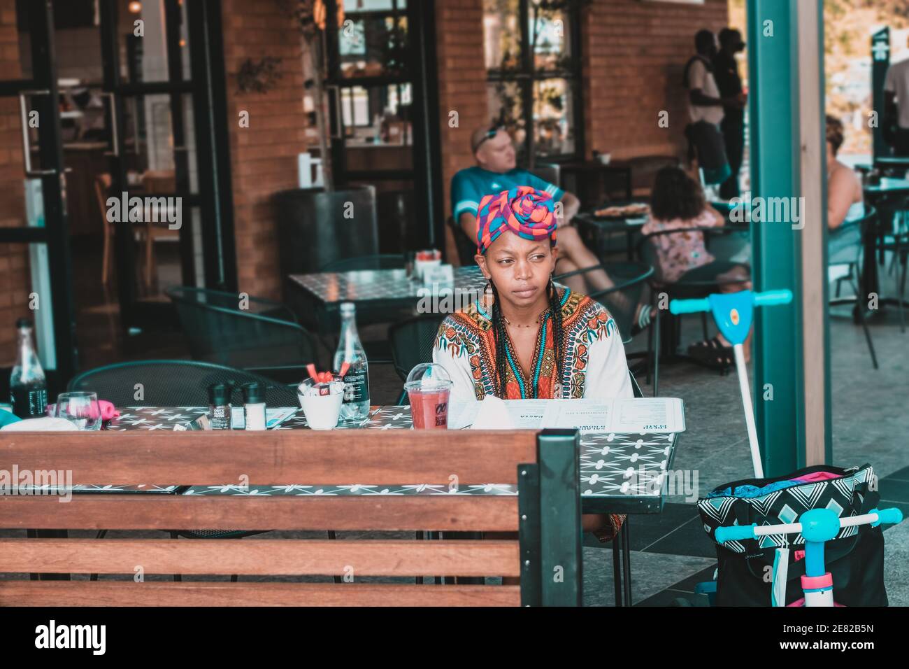 Madre africana in un ristorante con un frullato e aperto menu Foto Stock