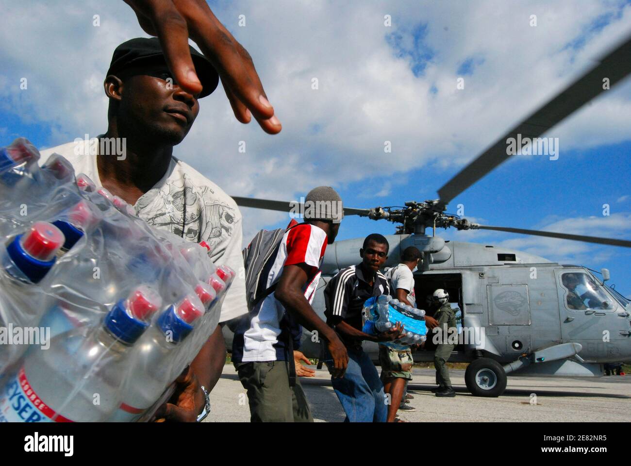 I lavoratori haitiani scaricano le forniture per il programma alimentare Mondiale delle Nazioni Unite all'aeroporto di Jacmel, a sud-ovest di Port-au-Prince 20 gennaio 2010. Un nuovo terremoto ha scosso la devastata capitale haitiana Port-au-Prince all'inizio di mercoledì, rastrellando edifici già distrutti e scatenando il panico tra i sopravvissuti del terremoto devastante della scorsa settimana. Le truppe canadesi stanno lavorando a Jacmel per fornire aiuti. REUTERS/Matthew Bigg (HAITI - Tags: TRASPORTO IN AMBIENTE DISASTROSO) Foto Stock