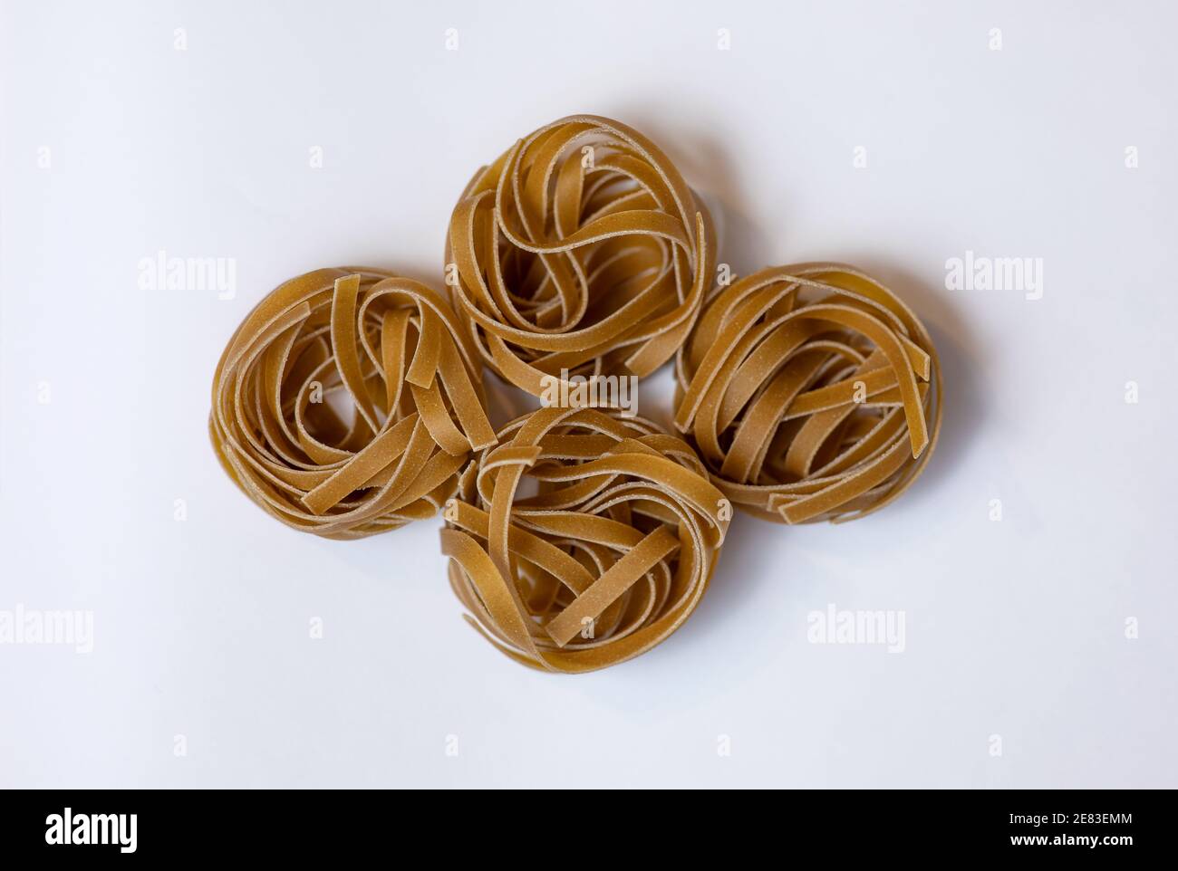 Pasta bruna grezza integrale Tagliatelle su fondo bianco, fatta con farina di grano, ricca di nutrienti: Proteine, carboidrati e fibre Foto Stock