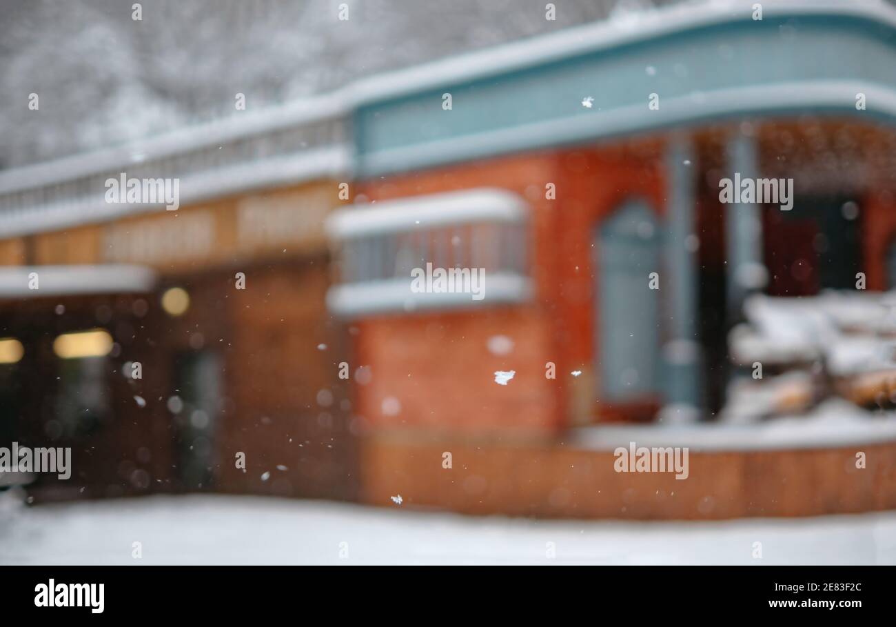 L'edificio è fuori fuoco. Retro vecchio bar esterno in legno in stile American Wild West. Sfondo per testo o immagini. Nevicare Foto Stock