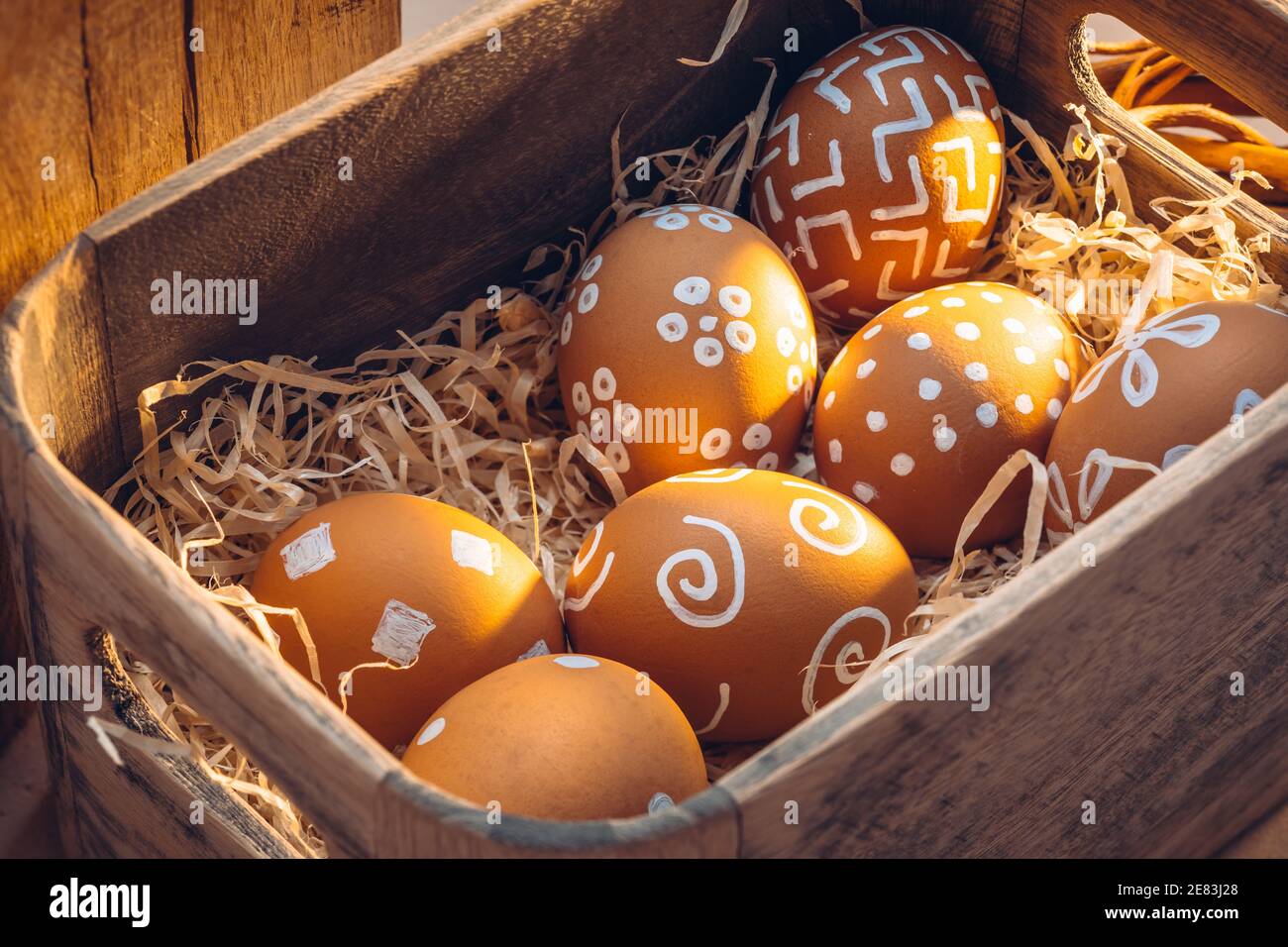 Pasqua in campagna. Tessuti naturali di fattoria con calde tonalità di luce solare. Uova marroni con motivi bianchi Foto Stock