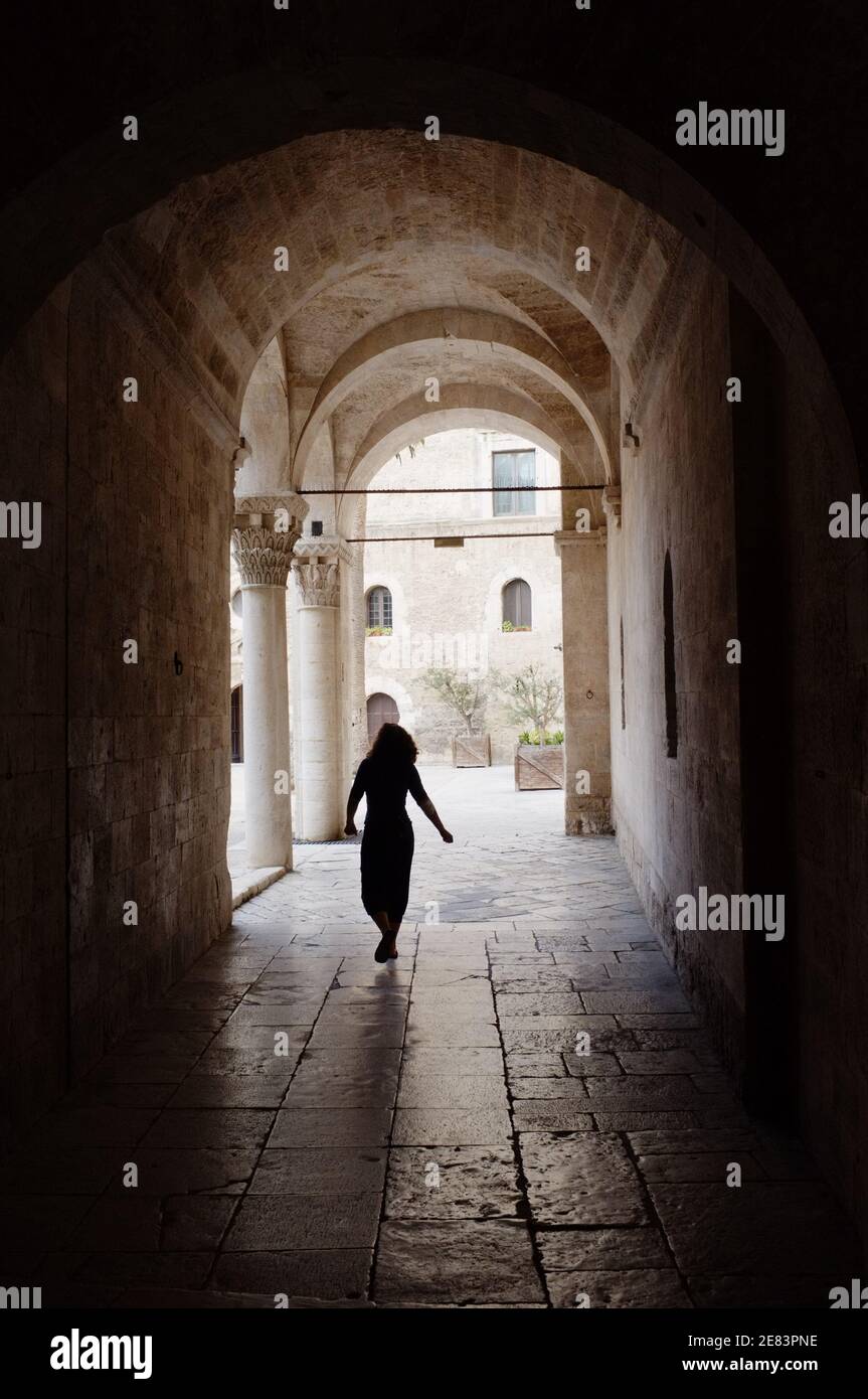 Bari, Italia - 08 luglio 2013: Una giovane donna attraversa gli alti archi che conducono al cortile del Castello Normanno-Svevo nel centro storico di Bari. Il CA Foto Stock