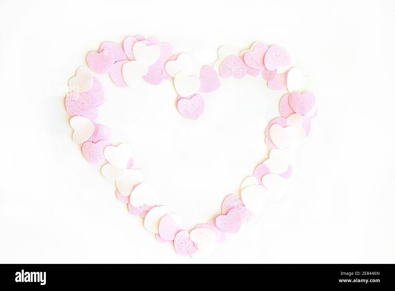 Confetti a forma di cuore rosa e bianco su sfondo bianco Foto Stock