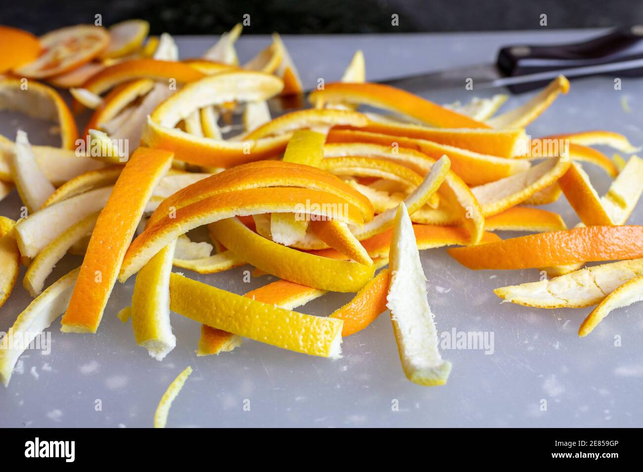 Fette di bucce di arancia e limone su un tagliere per la preparazione della loro preparazione in bucce candite Foto Stock
