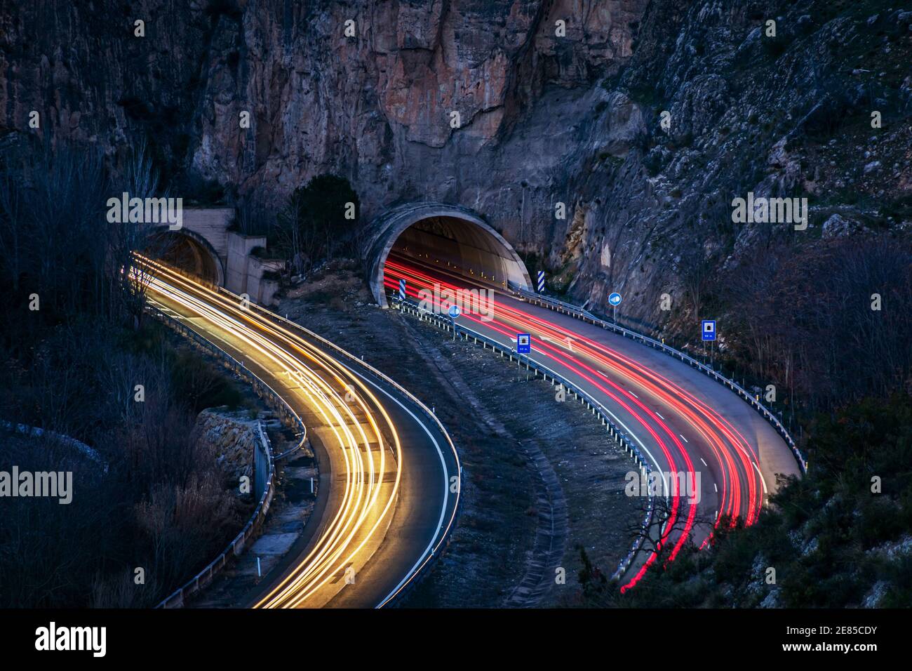 Lunga esposizione su un'autostrada che entra in alcuni tunnel, lasciando i raggi di luce sui veicoli sulla strada. Foto Stock