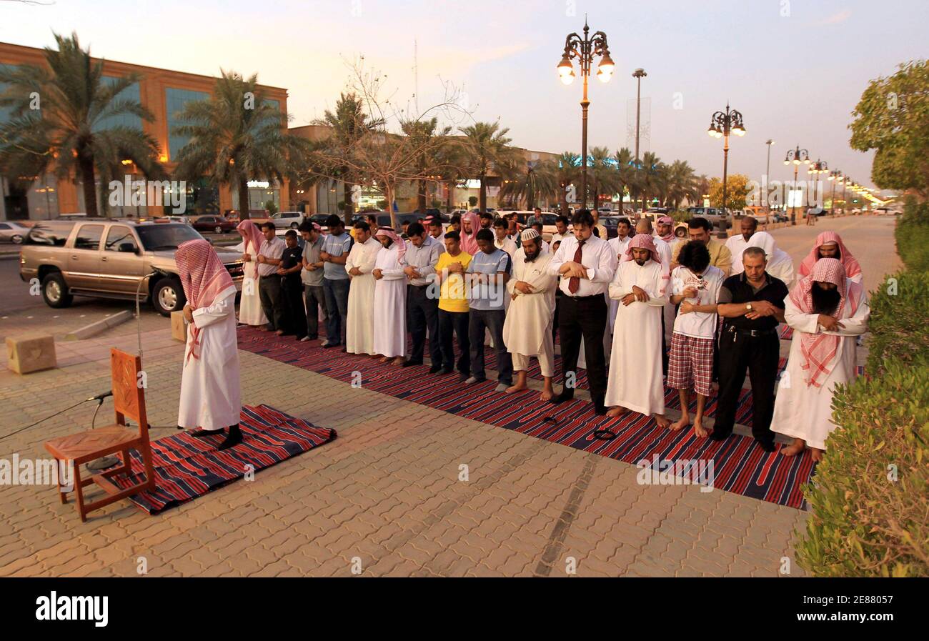 Members of the Committee for the Promotion of Virtue and Prevention of Vice, or religious police, perform dusk prayers with Saudi youth on the street outside coffee shops in Riyadh June 27, 2010. The men conducted the prayers during half-time of the World Cup soccer match between Germany and England, which they had been watching. The police have been ensuring that people watching World Cup soccer matches at the coffee shops continue to conduct their prayers during the duration of the soccer tournament. REUTERS/Fahad Shadeed (SAUDI ARABIA - Tags: SPORT SOCCER WORLD CUP RELIGION) Foto Stock