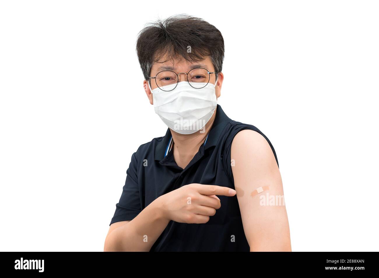 Un uomo asiatico di mezza età che indossa una maschera medica che punta ad un braccio iniettato con un vaccino. Foto Stock