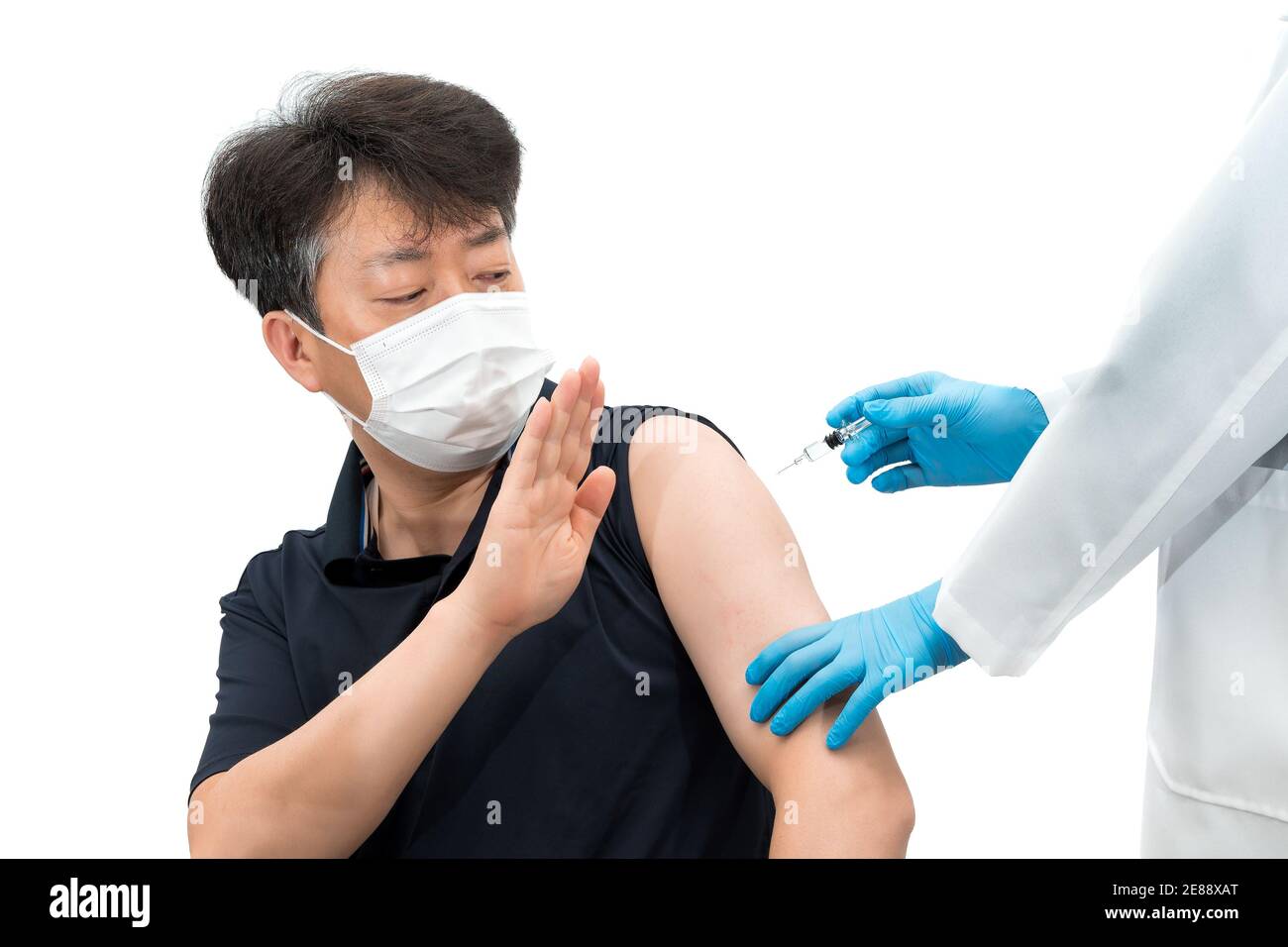Uomo asiatico di mezza età che indossa una maschera medica che rifiuta di iniettare il vaccino. Foto Stock