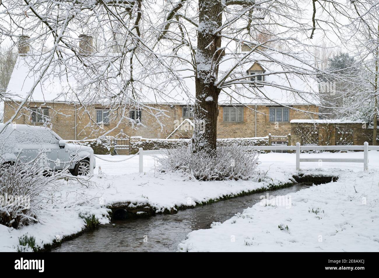 Stream e Cotswold cottage in pietra nella neve. Swinbrook, Cotswolds, Oxfordshire, Inghilterra Foto Stock